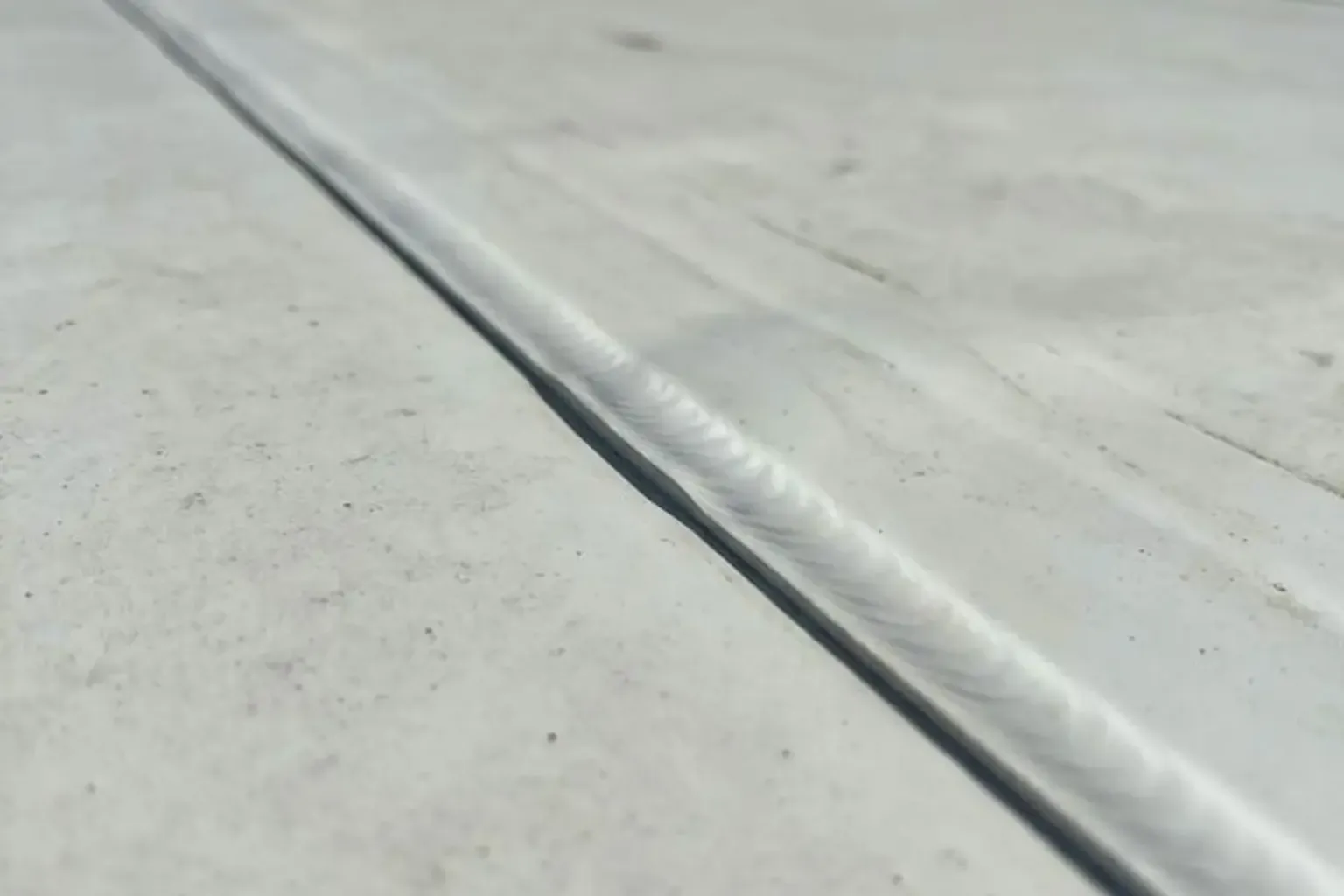 Documentary-style iPhone photo of commercial roof leak detection and seam repair on a low-slope building in Provo, Utah. Natural lighting.