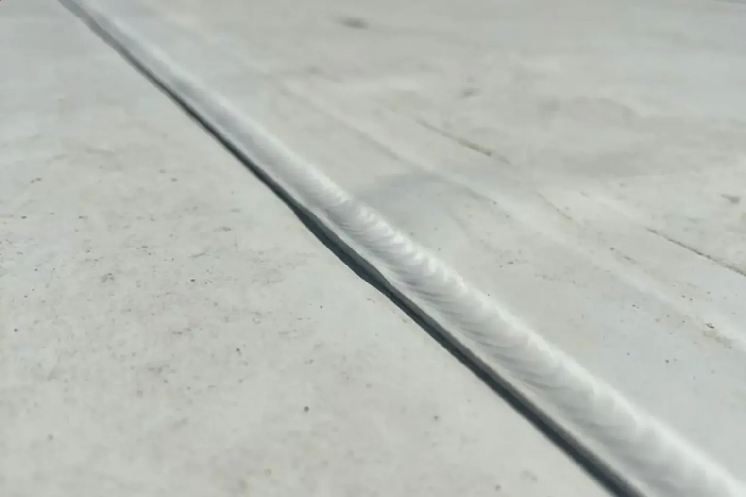 Documentary-style iPhone photo of commercial roof leak detection and seam repair on a low-slope building in Provo, Utah. Natural lighting.